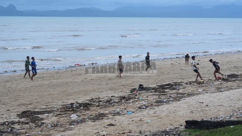 Sekelompok lelaki belia asyik bersepak bola di sebelahnya.