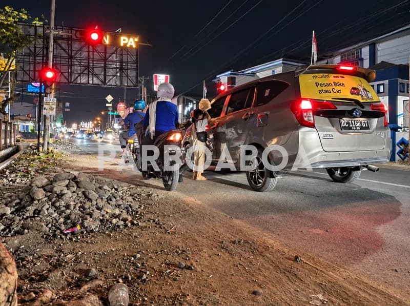 Aria menawarkan kerupuk ubi kepada pengendara saat lampu merah menyala (Foto: Eka Musriang/PARBOABOA)