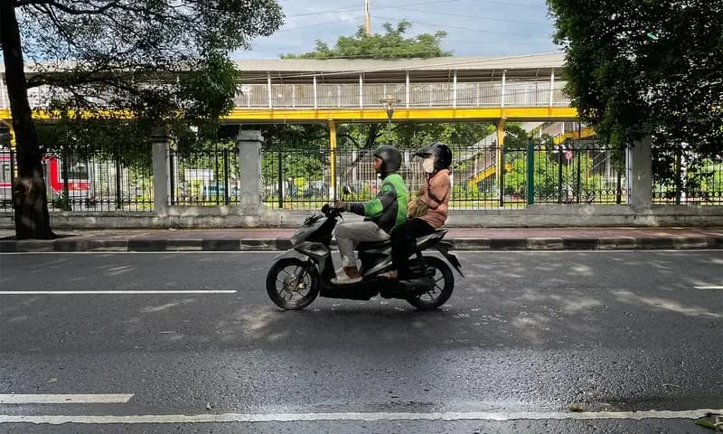 Seorang pengemudi ojol sedang melintas di jalan Palmerah Timur, Jakarta Barat (Foto: PARBOABOA/Defri Ngo).