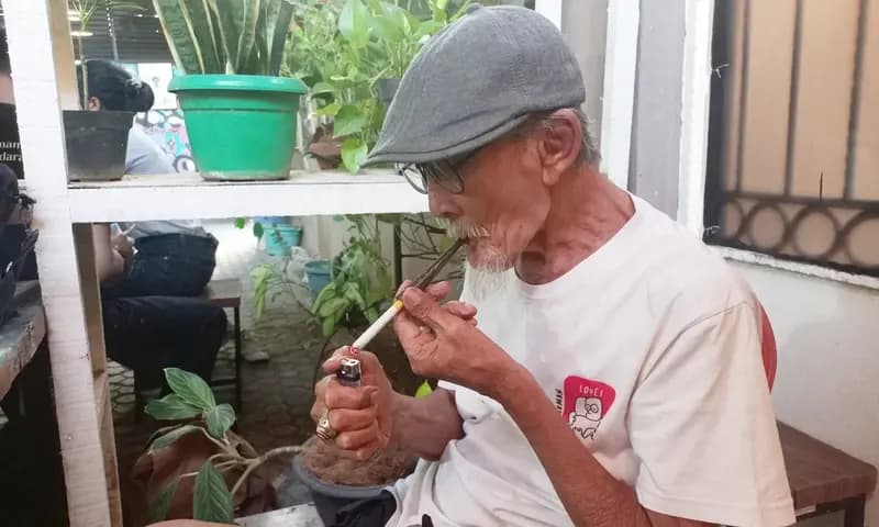 Effendi Saleh menyulut api ke rokok kreteknya saat ditemui di Kantor KontraS, 12 September lalu. (Foto: PARBOABOA/Muazam)