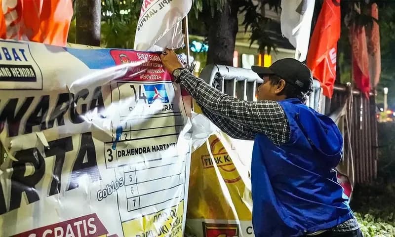 Seorang petugas sedang membersihkan spanduk kampanye yang dipasang di pinggir jalan (Foto: Instagram/@kotajakartapusat)