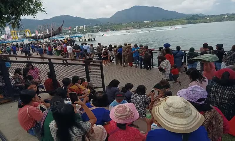 Masyarakat menyaksikan para pembalap yang tengah menjajal trek Danau Toba di pagar dari arena tribun venue utama yang terletak di Pelabuhan Mulia Raja Napitupulu Balige. (Foto: PARBOABOA/PutraÂ Purba)
