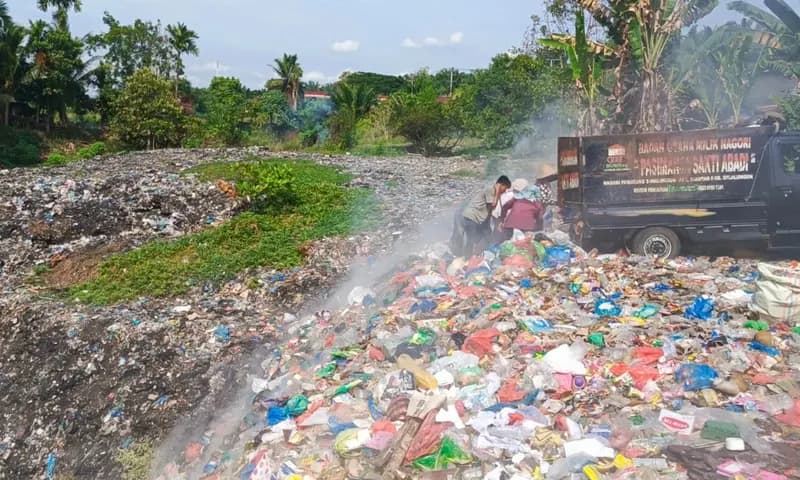 Para petugas pengakut sampah membakar sampah di TPA Jalan Asahan Batu VIII. (Foto: PARBOABOA/Jeff Gultom)