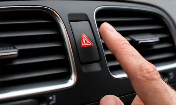 Tombol lampu hazard di panel dashboard mobil.