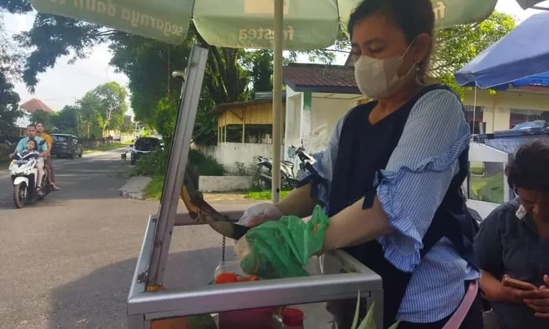 Salah satu pedagang rujak yang menggunakan masker dan sarung tangan untuk menjaga kebersihan makanan yang dijual. (Foto: Parboaboa/Kristianni Halawa)